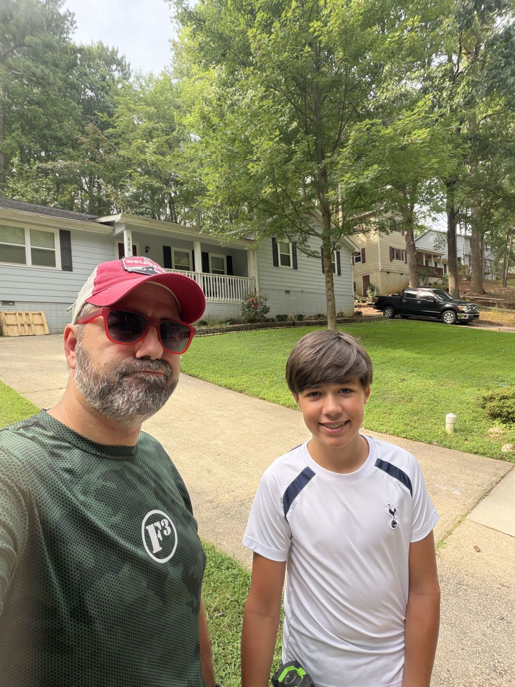 An F3 man and a teen in front of a freshly mowed lawn