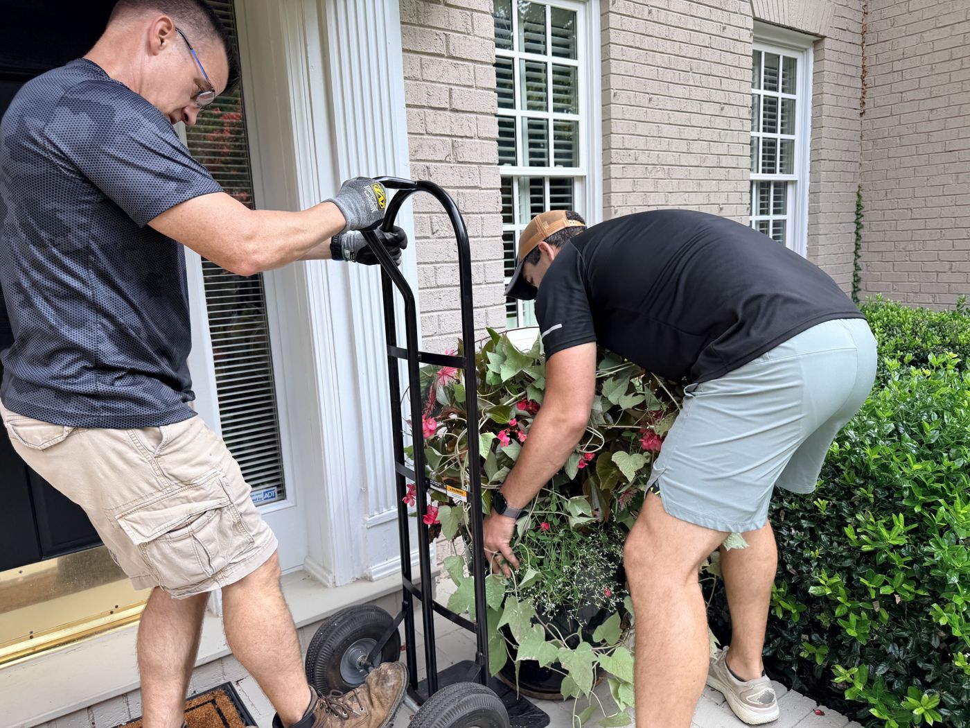 Two F3 men moving a large planter with a hand truck